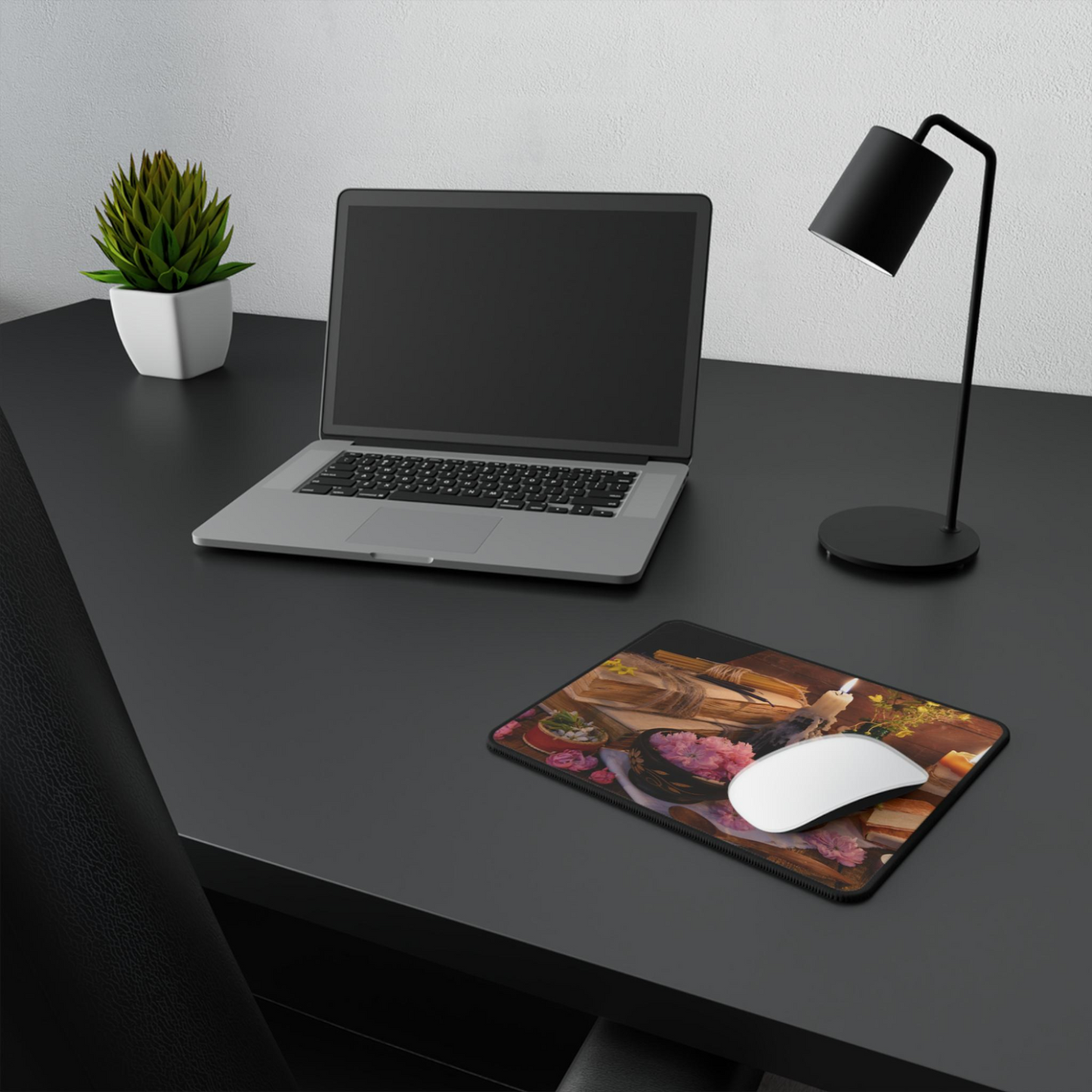 Laptop on a desk with a mouse and mouse pad, accompanied by a lamp and plant.
