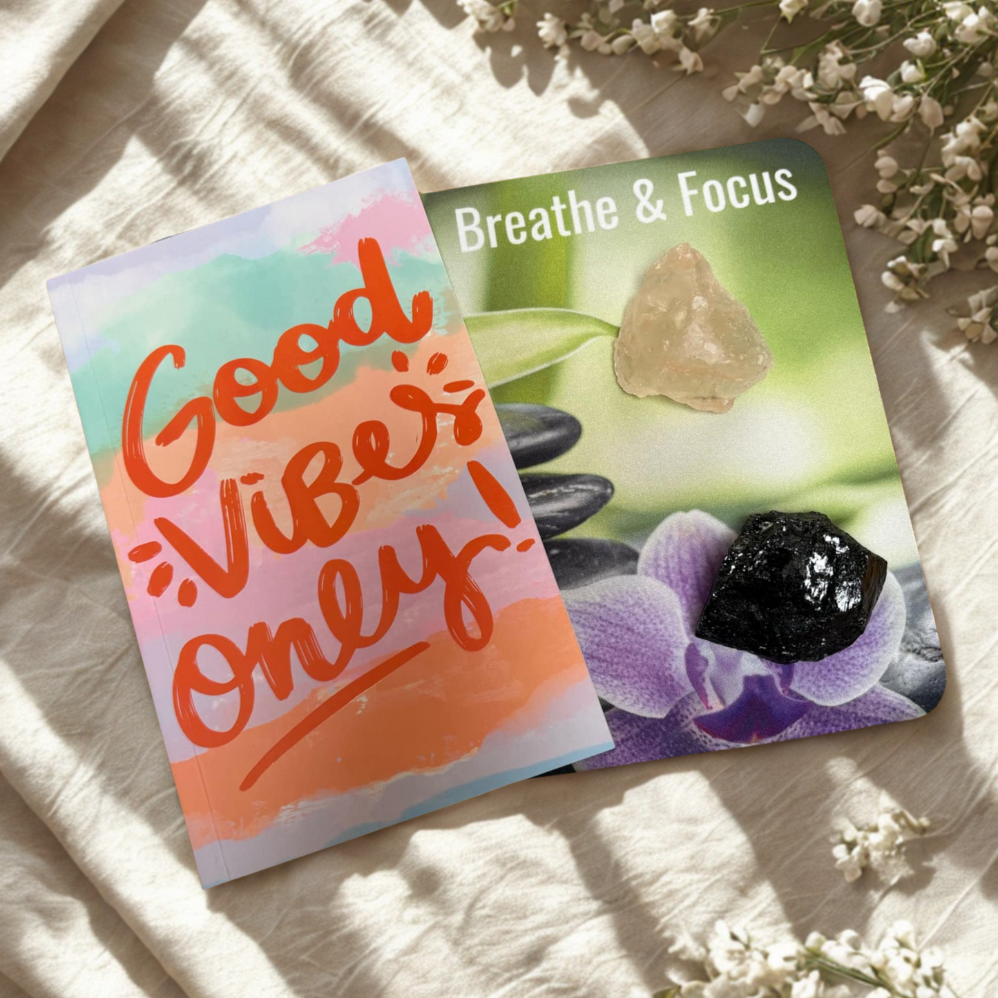Good Vibes Only Notebook, Breathe & Focus affirmation mouse pad, black tourmaline and salt chunk on a light fabric background with flowers.