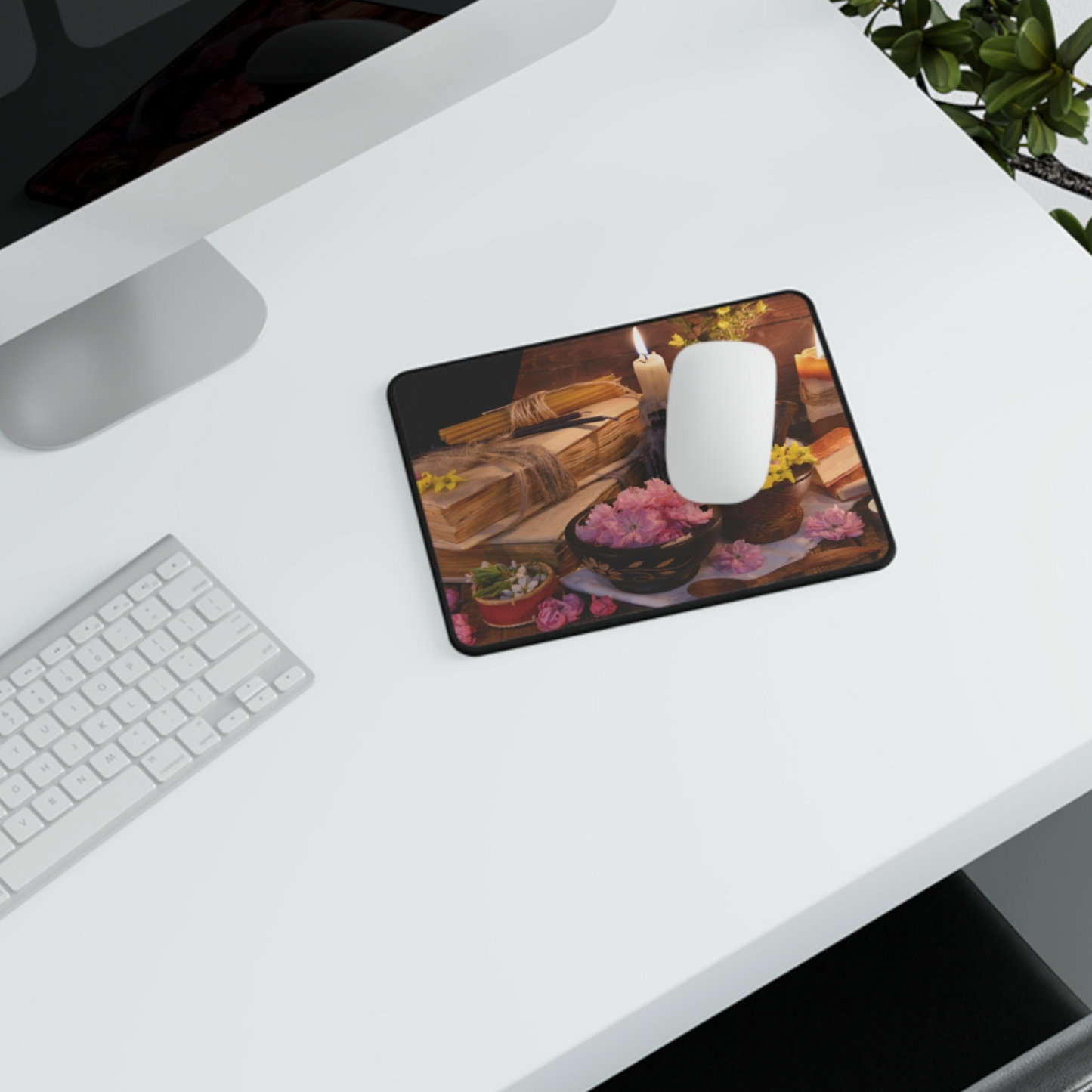 Mouse pad with a design of a candle, books, and flowers on a desk with a computer mouse.