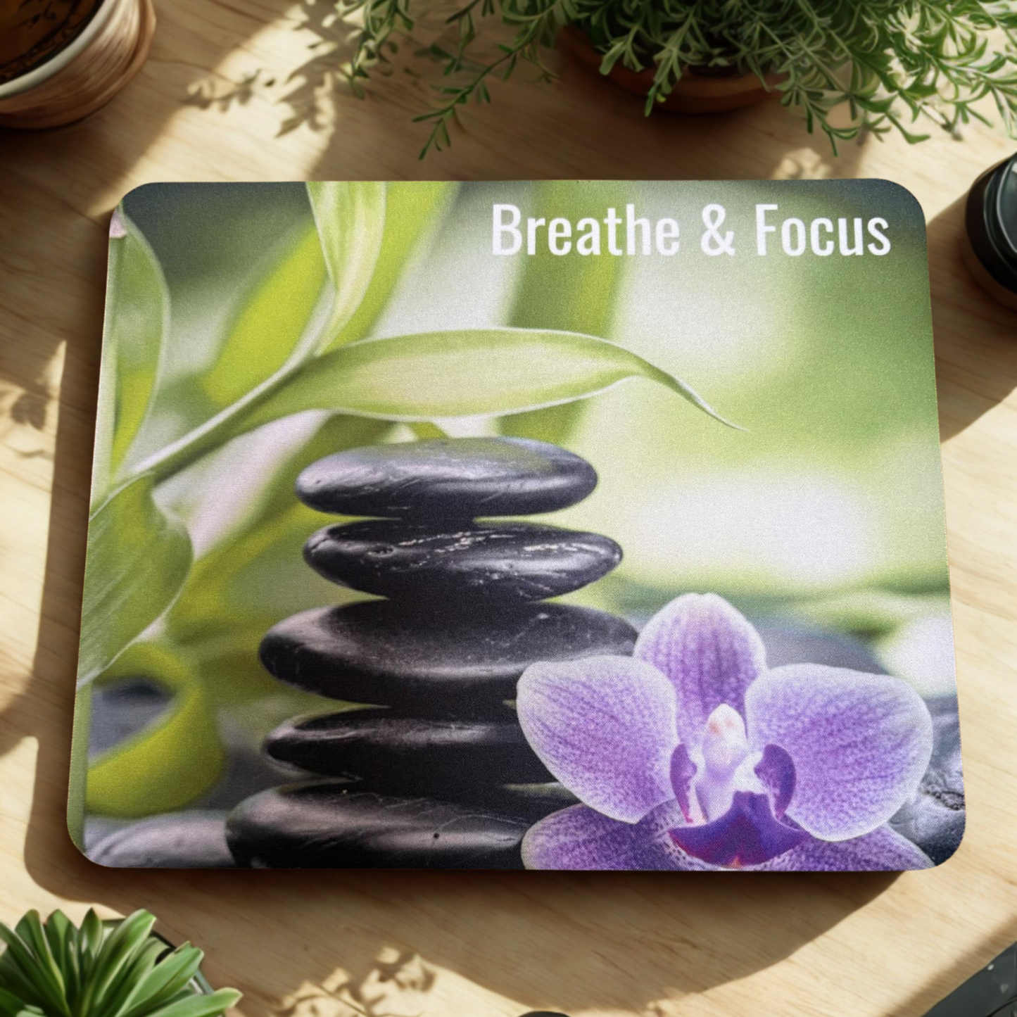 Mouse Pad with stones, orchid, and green leaves on a wooden surface with 'Breathe & Focus' text.