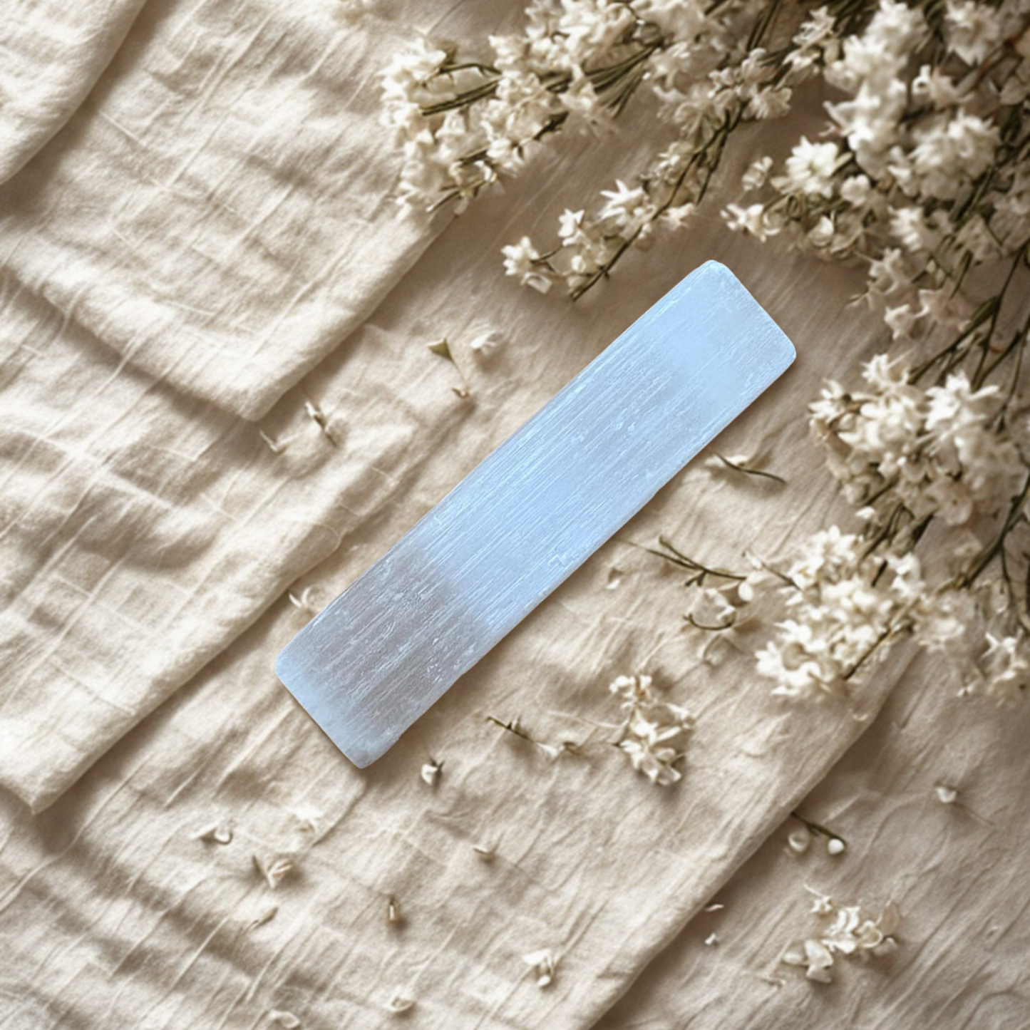 Selenite rod on fabric surface with small white flowers