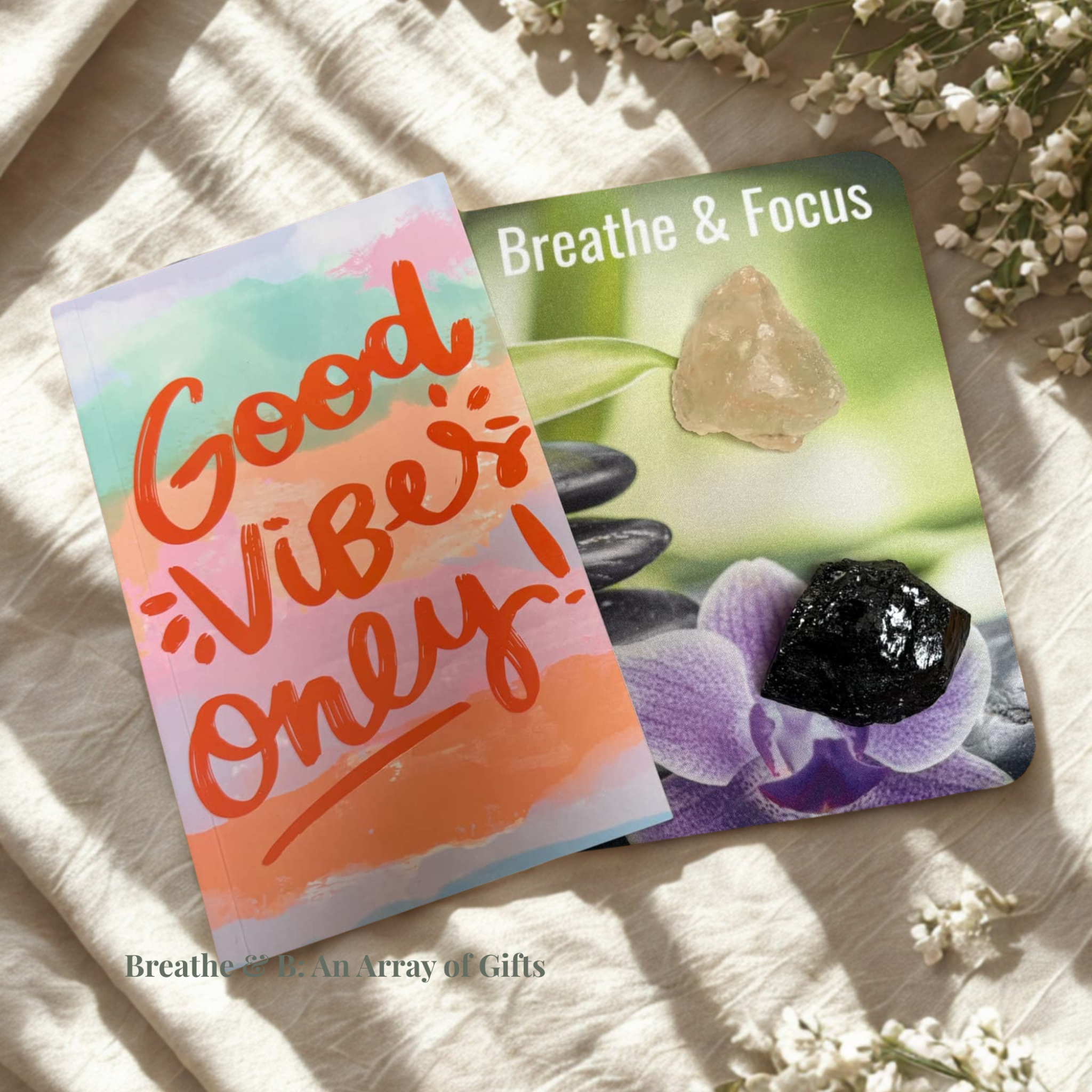 Affirmation Mouse Pad "Breathe & Focus", Good Vibes Only notebook, salt chunk and black tourmaline on a textured surface with flowers around.