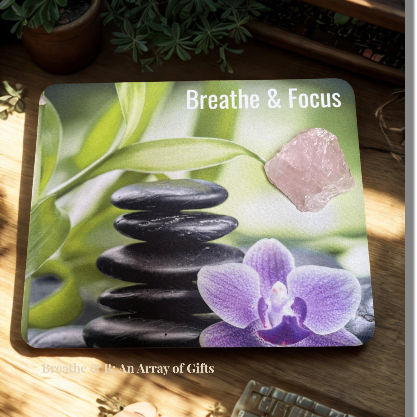 Affirmation Mouse pad with balancing stones and orchid, with a rose quartz crystal on a wooden surface