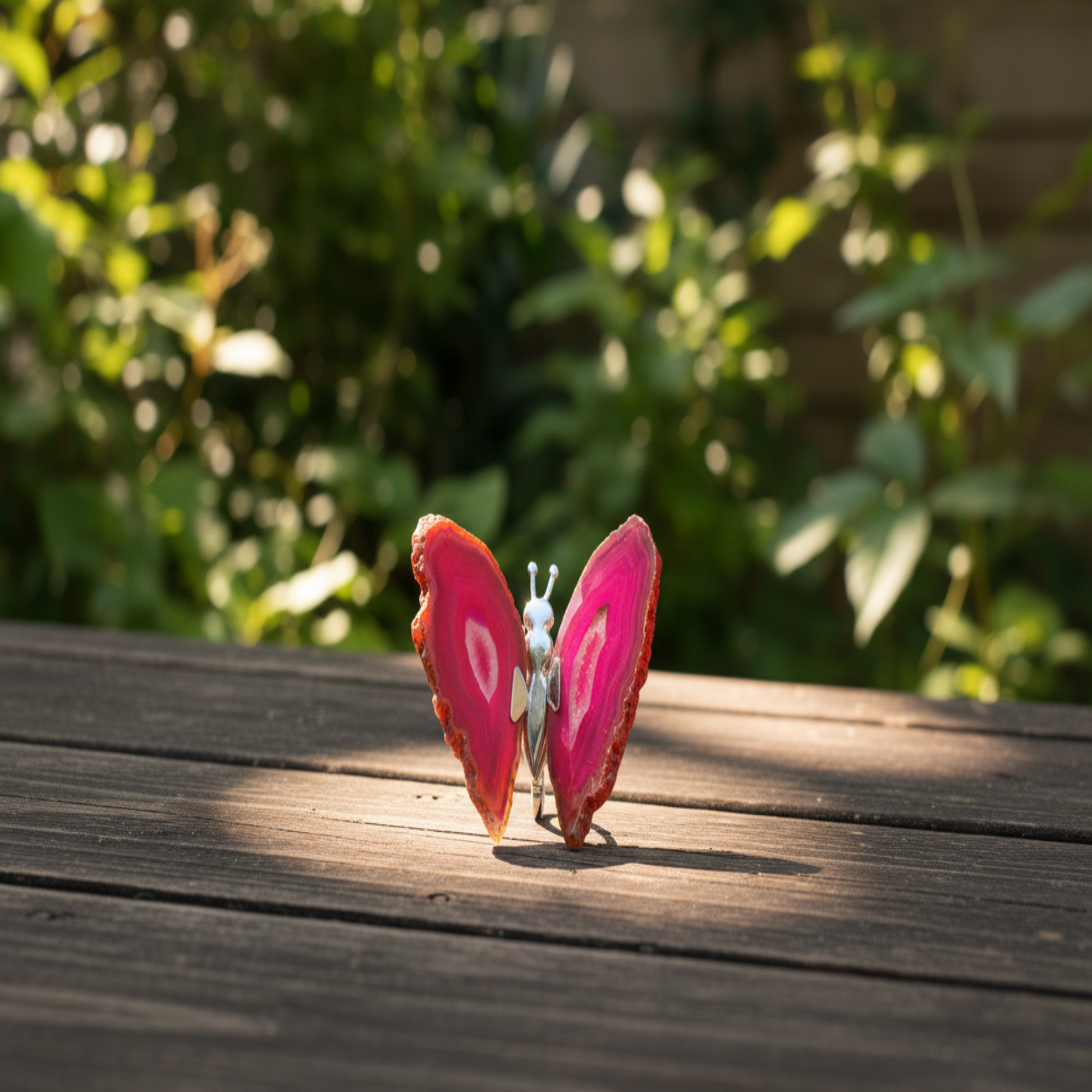 Agate Pink Butterfly on a wooden surface with a blurred green background