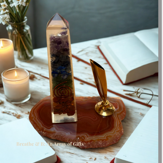 Orgonite Obelisk on an brown agate slice with pen holder with candles and books in the background
