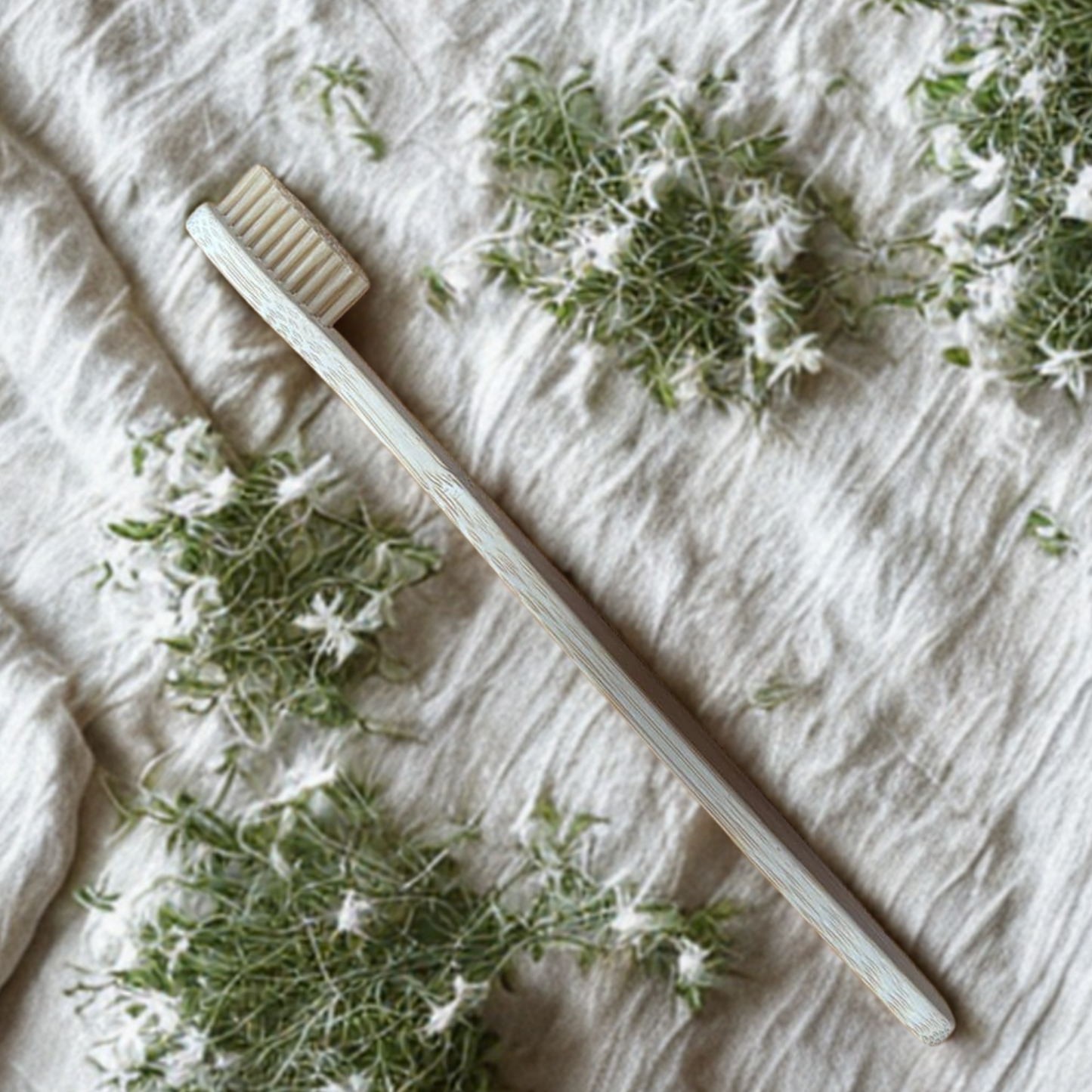 Bamboo adult  toothbrush on a textured fabric background with greenery