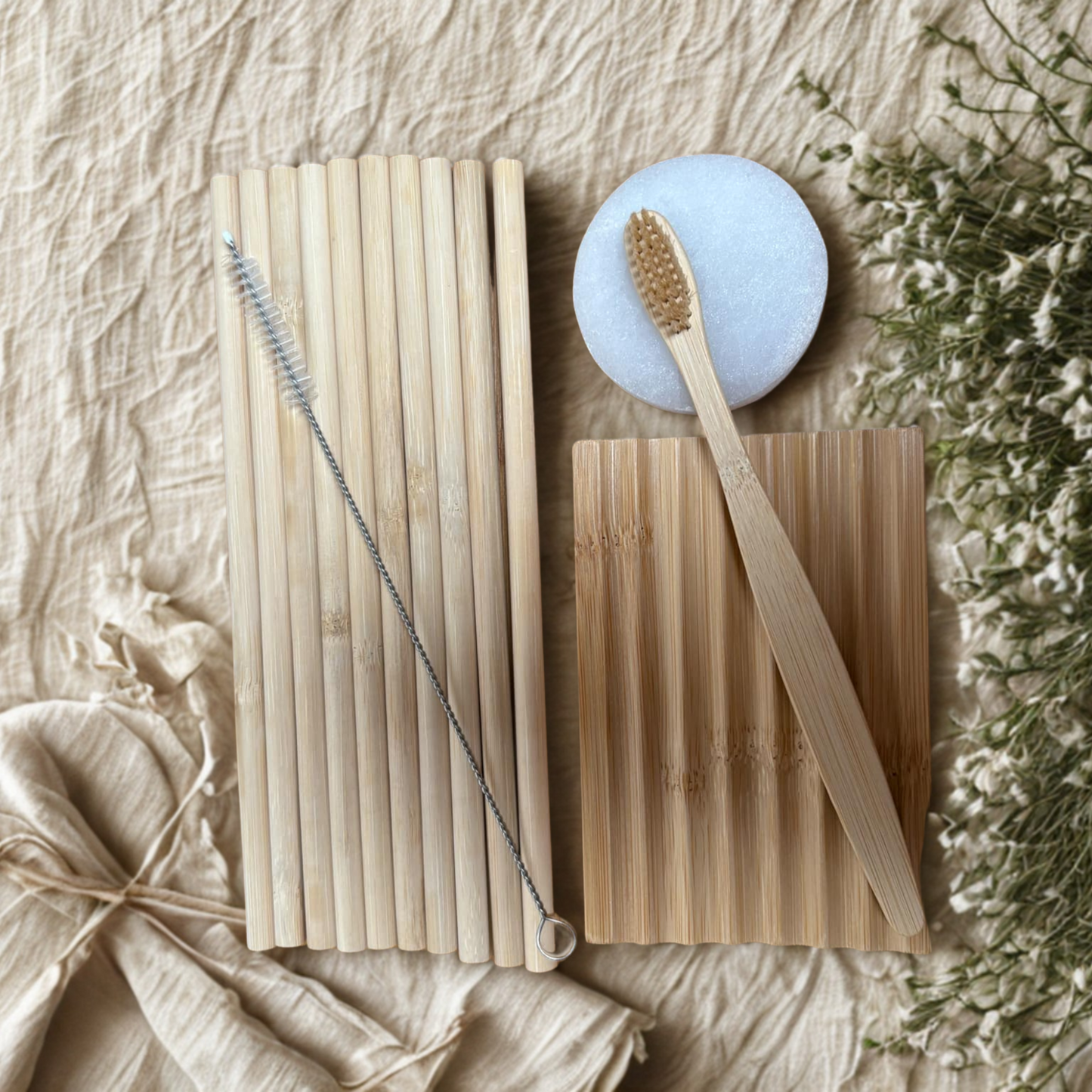 Bamboo straws, cleaning brush, and wooden soap dish, bamboo toothbrush and selenite plate on a natural background