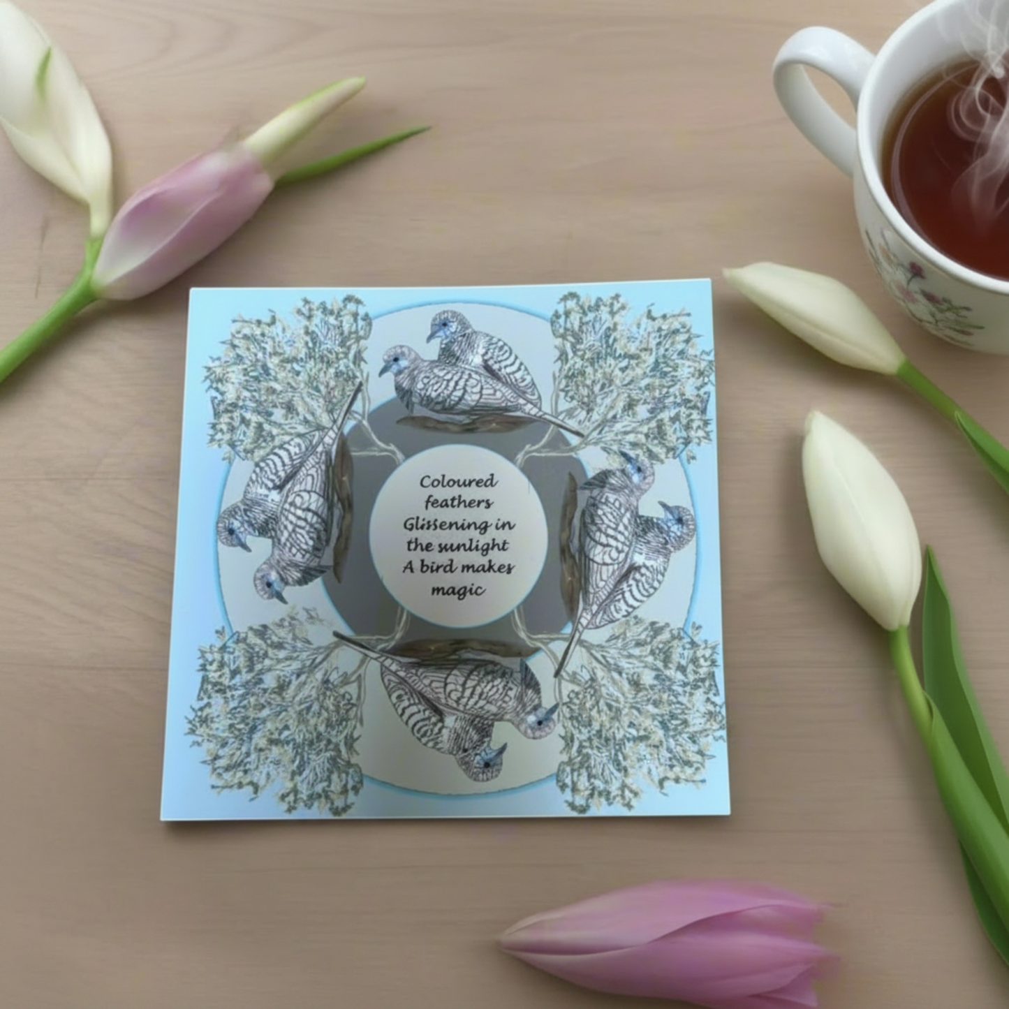 Bird greeting card placed on table with a cup of tea with soft natural styling flat lay
