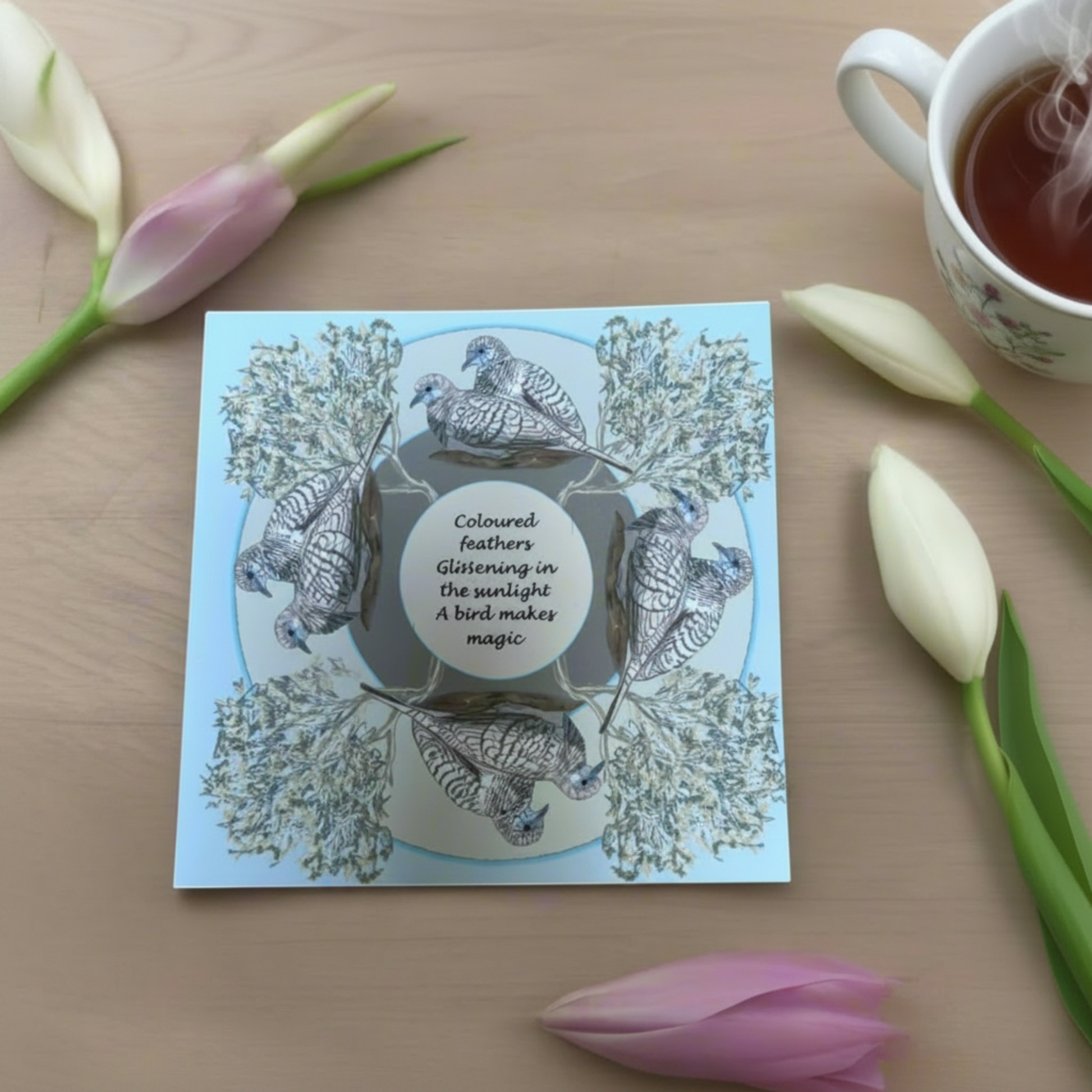 Bird greeting card placed on table with a cup of tea with soft natural styling flat lay