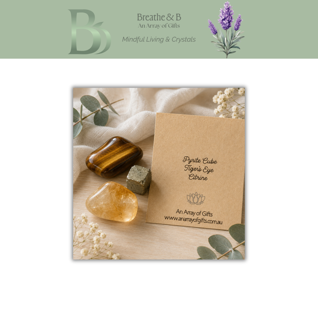 A square product presentation card for a Breathe & B: An Array of Gifts of  Abundance Prosperity Crystal Kit . The card is displayed on a light wood surface with a tiger's eye, pyrite cube, citrine tumble stone surrounded by eucalyptus leaves and dried flowers on a white fabric.