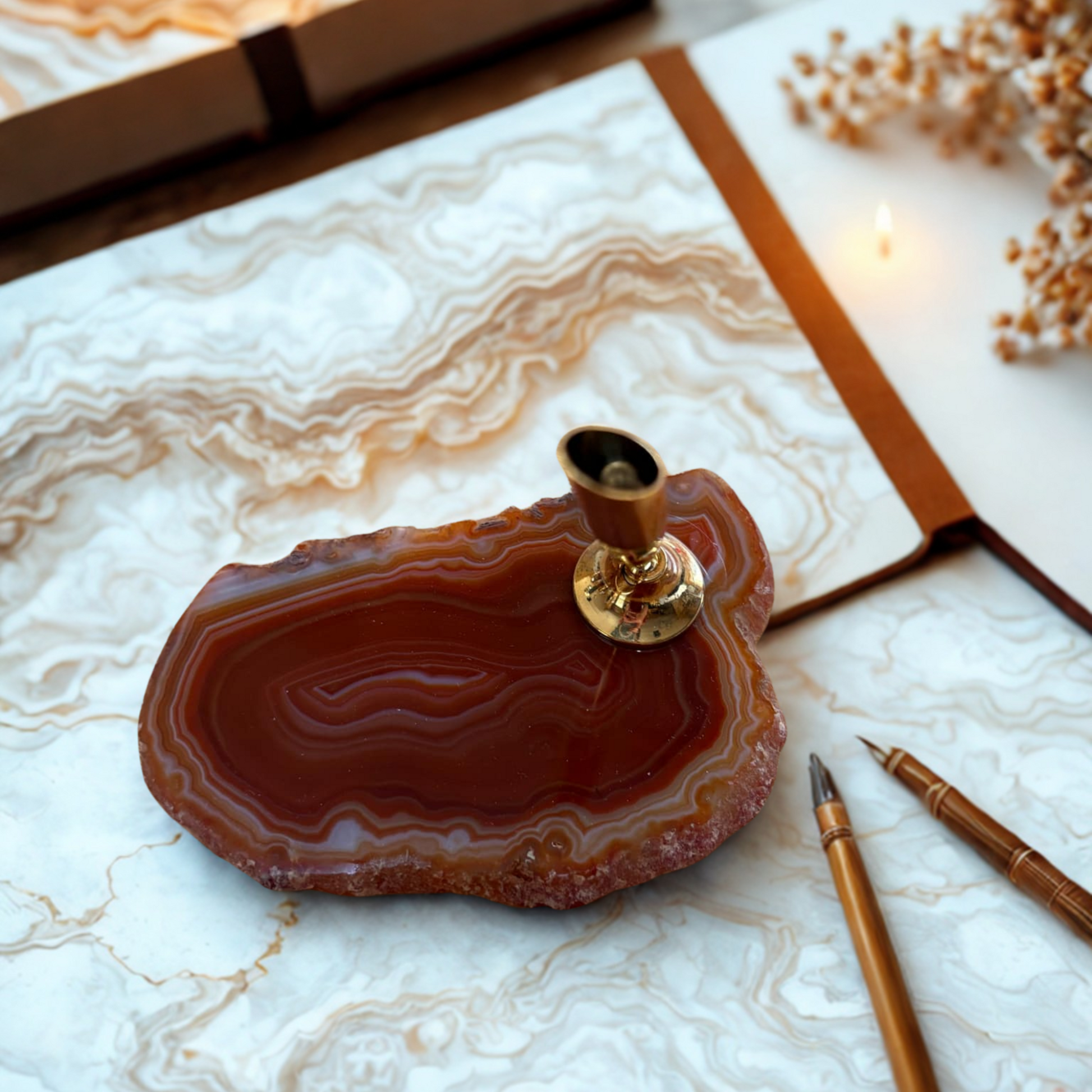Decorative pen holder on an brown agate stone with a pen and notebook in the background.