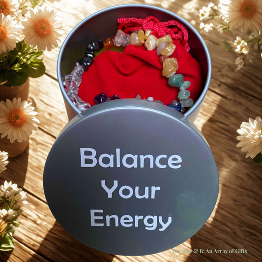 Chakra Healing Kit with seven tumbled crystals, chakra bracelet, affirmation card, red velvet pouch, and silver gift tin labeled 'Balance Your Energy' displayed on a wooden table.