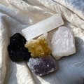 Crystal kit for calm and anxiety relief with amethyst, citrine, rose quartz, black tourmaline and selenite healing crystals flat lay on neutral background