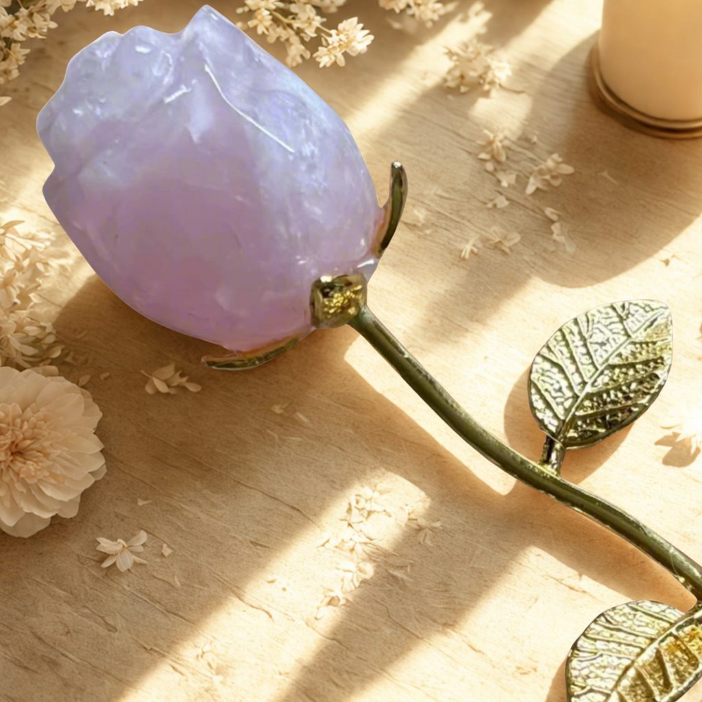 Decorative pink rose quartz on a wooden surface with flowers and a candle in the background