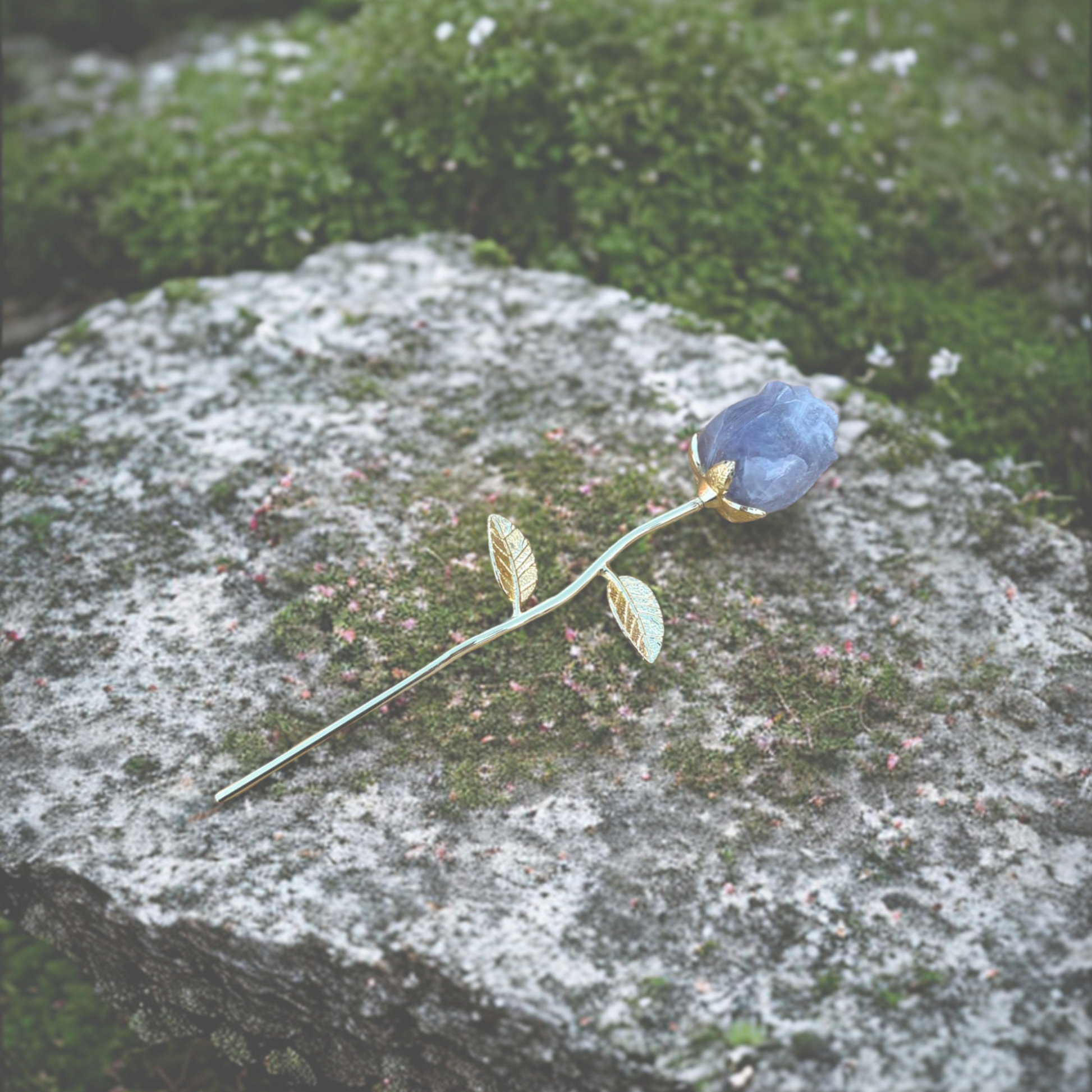 Gold stemmed rose with a purple stone on a mossy rock