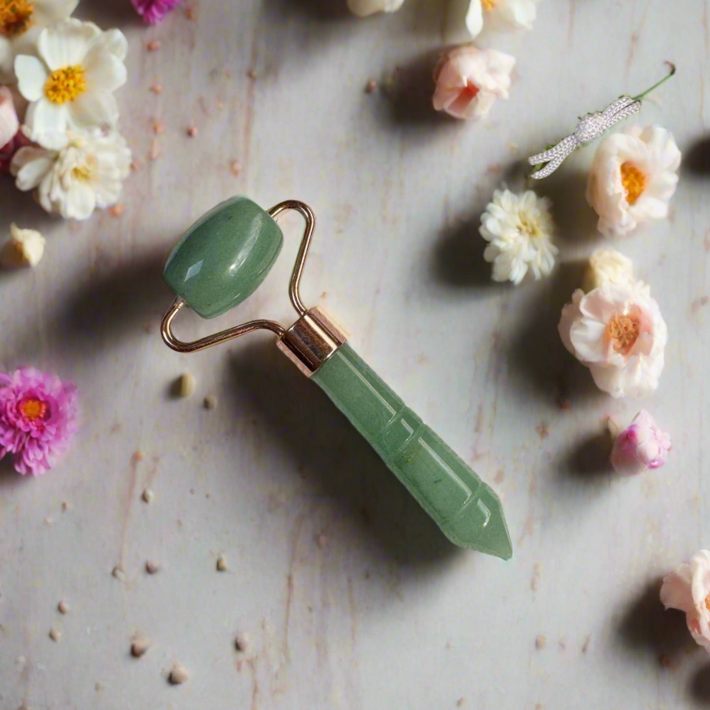 Green jade roller on a textured surface with flowers around