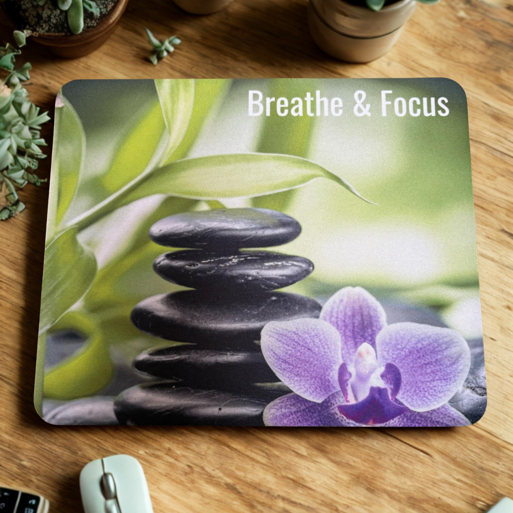 Mouse pad with stones, orchid, and 'Breathe & Focus' text on a wooden surface.