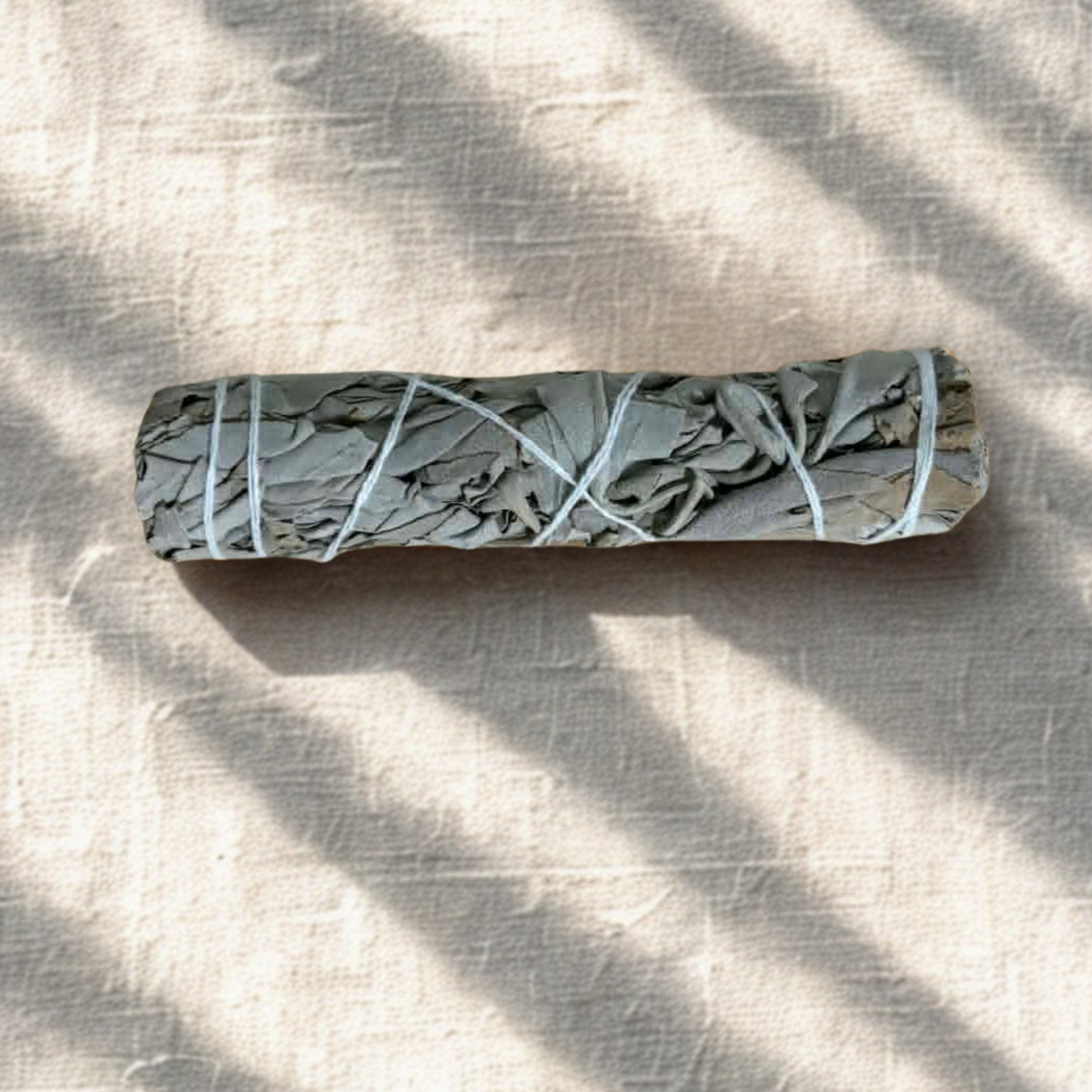 Natural dried sage smudge stick tied bundle used for energy cleansing, spiritual purification and mindfulness rituals on white line and subtle lighting