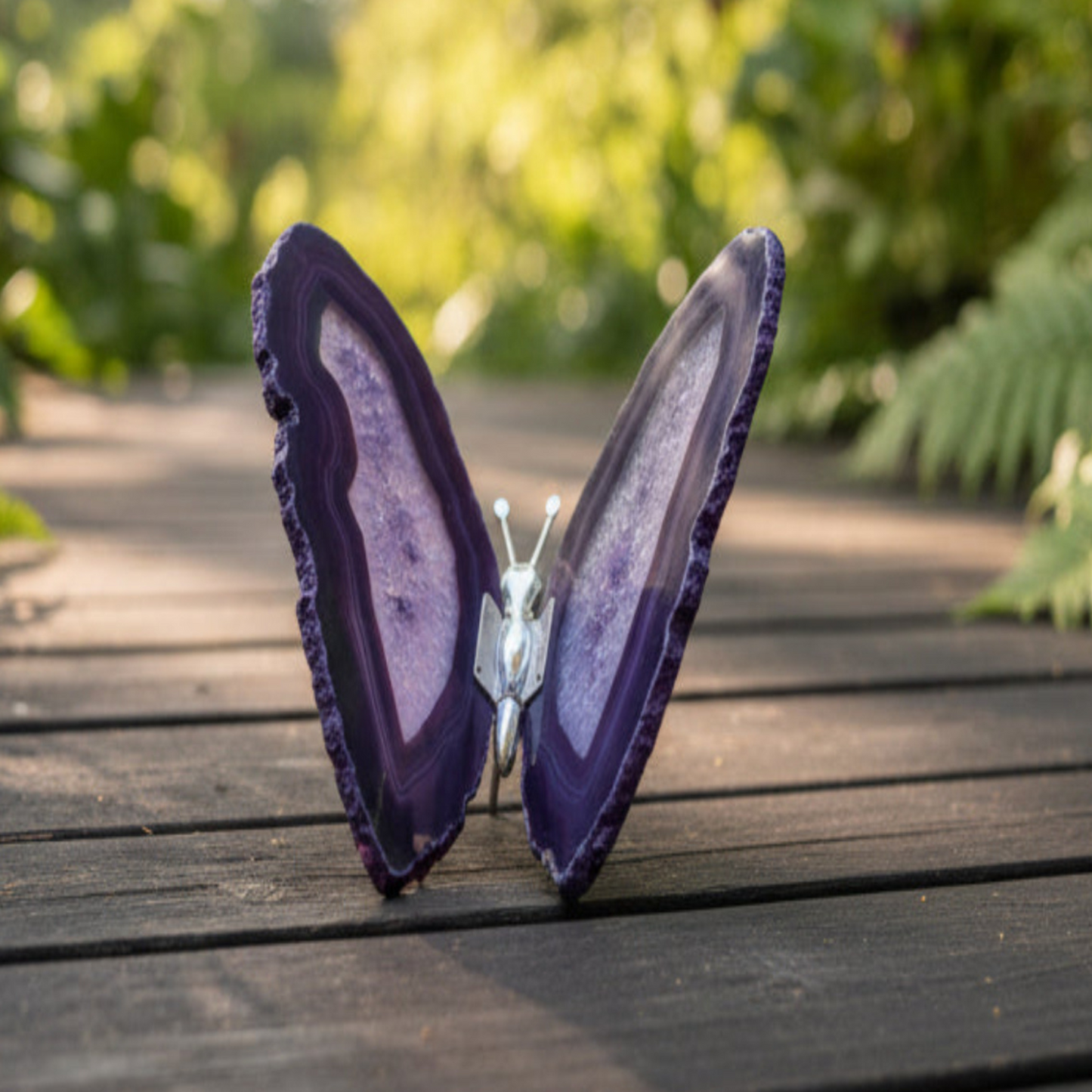 Purple agate butterfly sculpture on a wooden surface with a blurred natural background