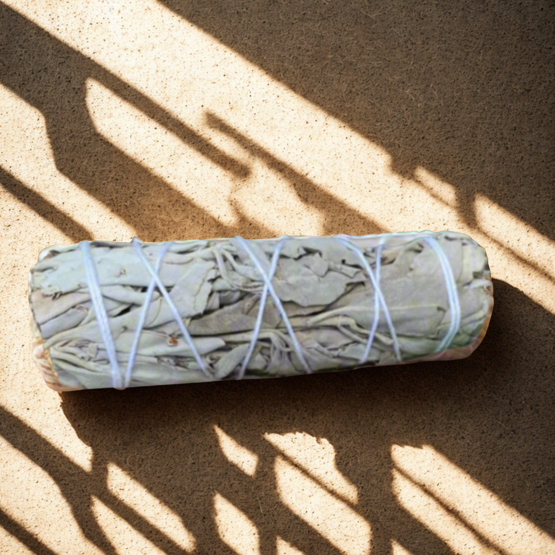 Rolled sage bundle tied with twine on a sandy surface