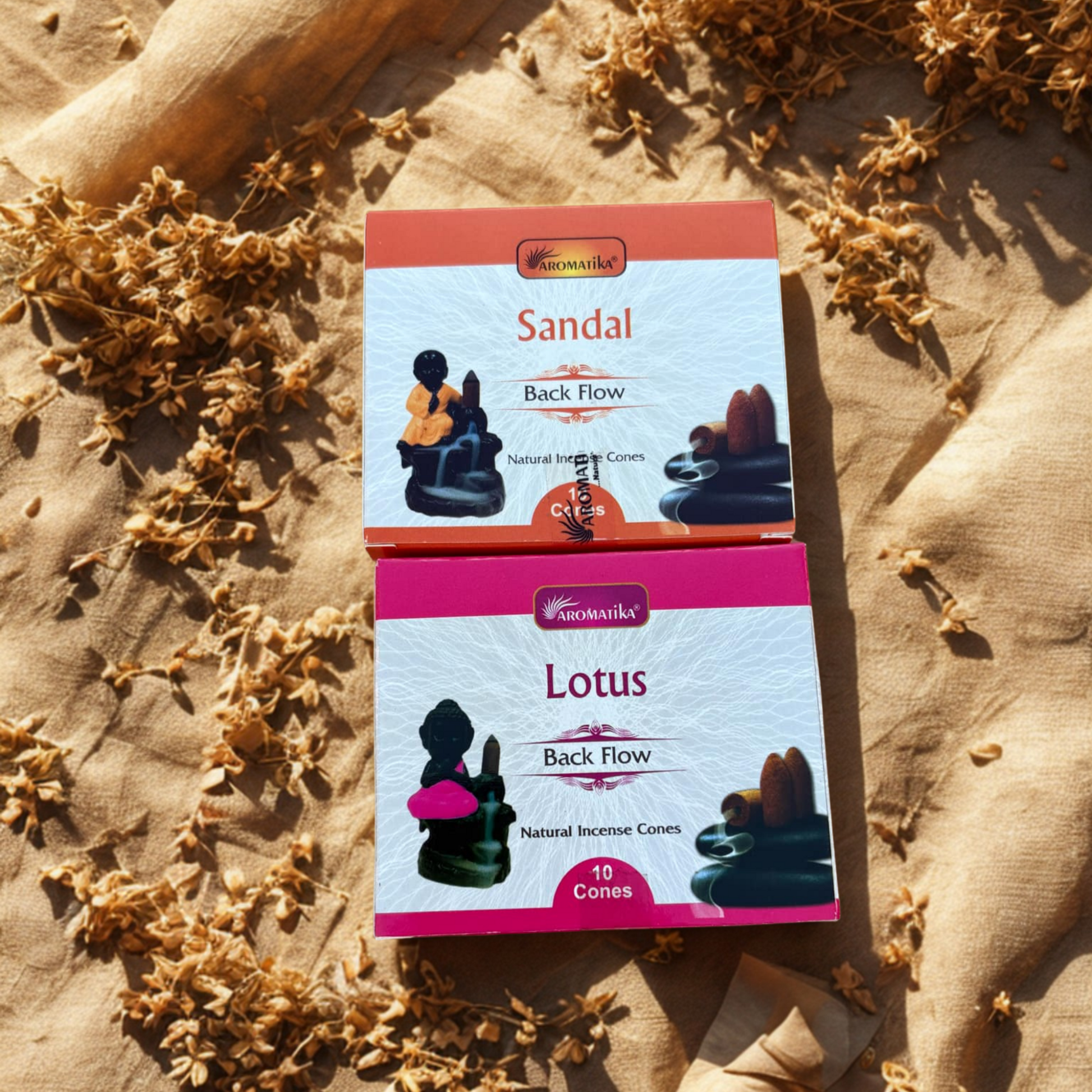 Two boxes of Aromatika incense cones, one labeled 'Sandal' and the other 'Lotus', on a textured surface with dried flowers.