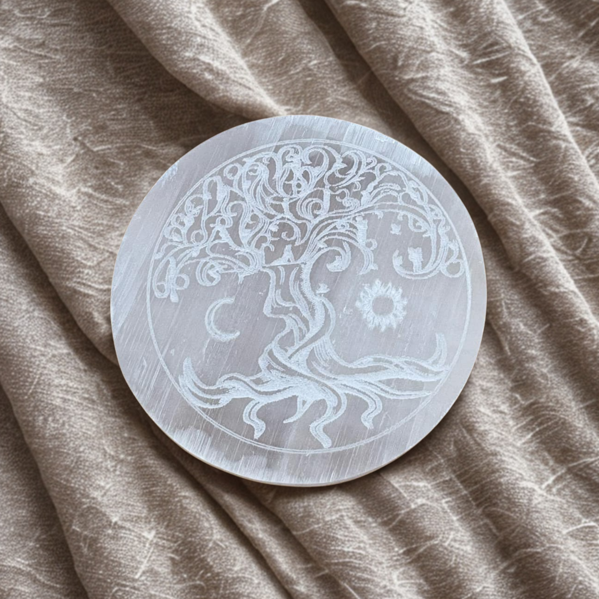 Decorative stone with tree of life design on a beige fabric background