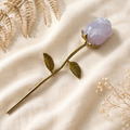 Decorative rose with a rose quartz crystal with a gold coloured stem, on a soft focus background