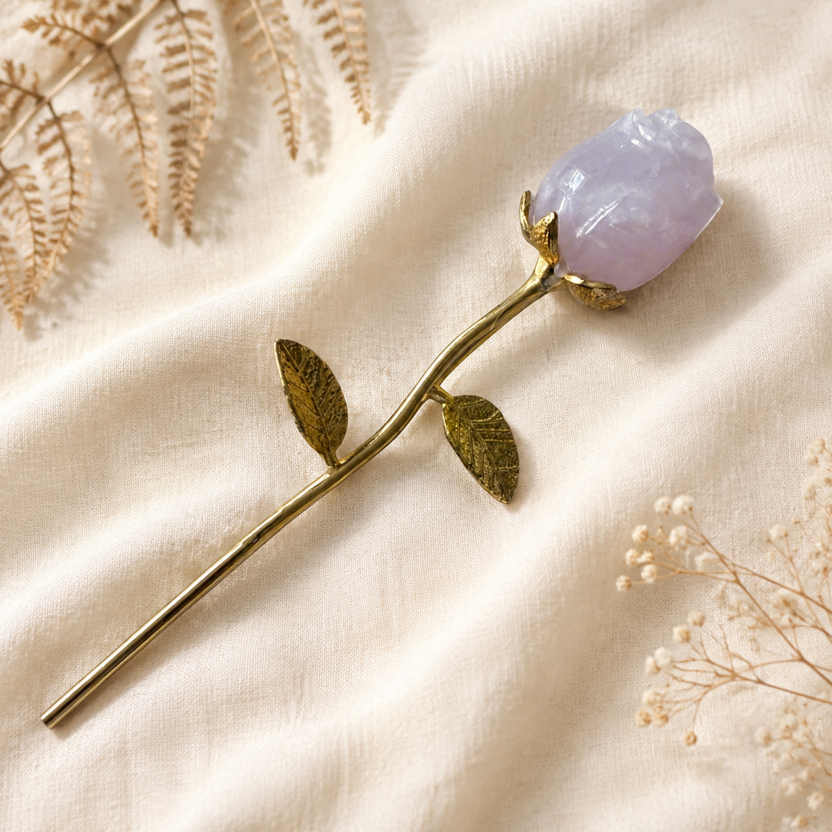 Decorative rose with a rose quartz crystal with a gold coloured stem, on a soft focus background